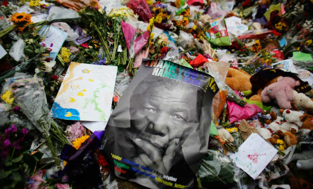 A poster of Nelson Mandela lays between flowers outside of his house in Johannesburg. -AP A poster of Nelson Mandela lays between flowers outside of his house in Johannesburg. -AP